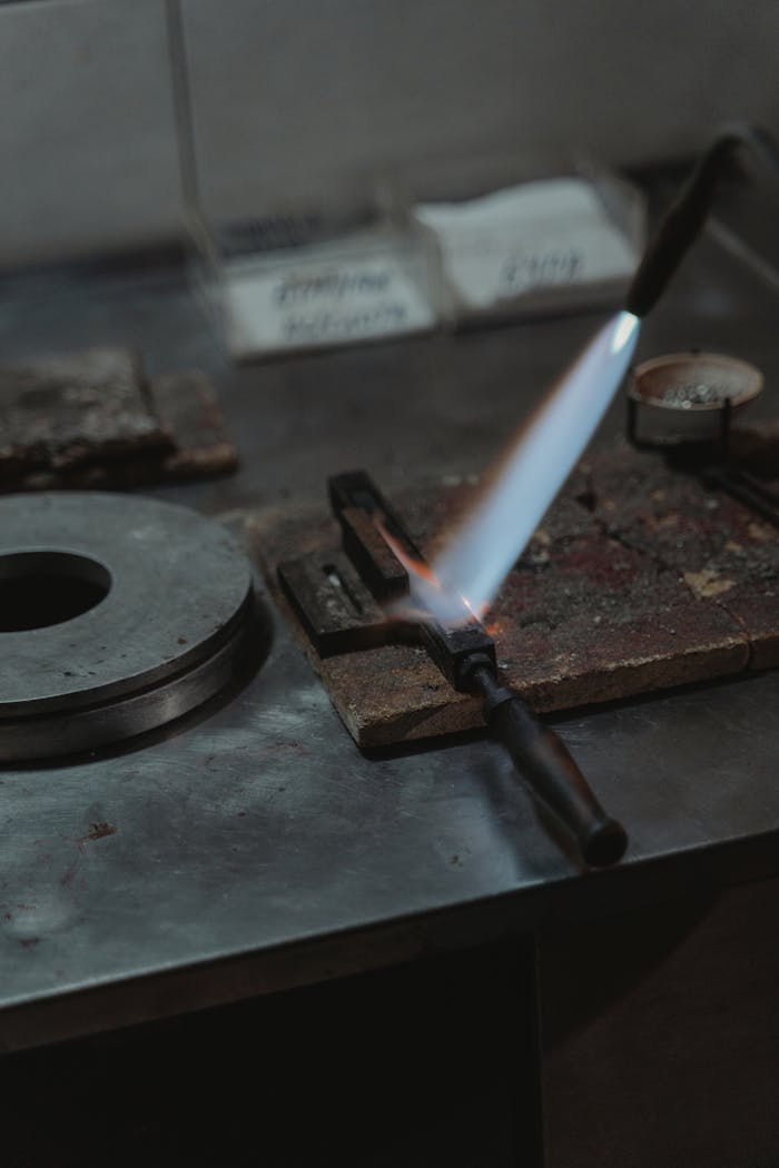 about-us Close-up of a lit blowtorch in an industrial workshop setting.
