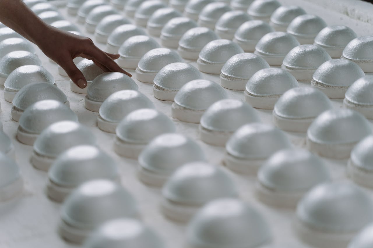 services-06 A person gently inspects rows of ceramic molds in a factory setting.