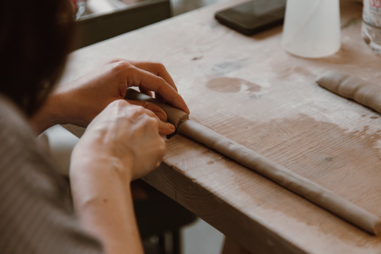 Close-up of a woman sculpting clay, highlighting delicate craftsmanship and artistry.